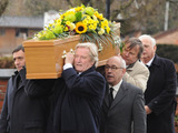 Residents of the street carry the coffin away.