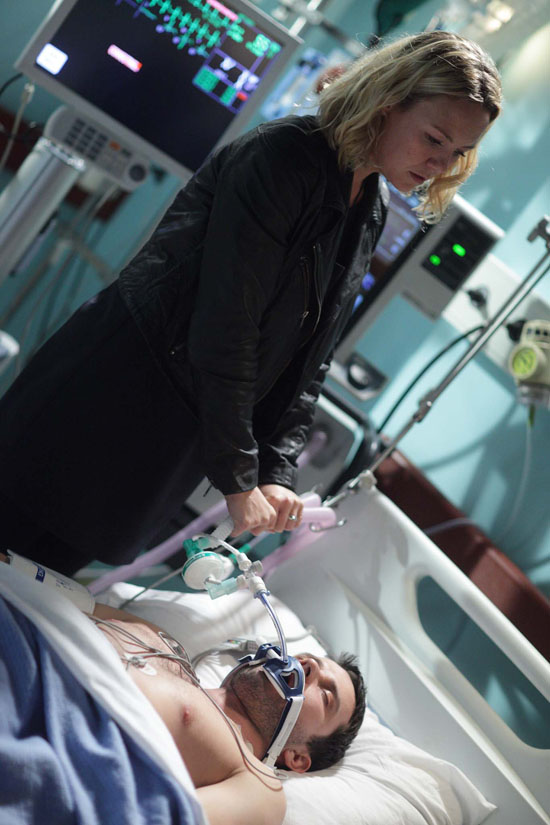 By his bedside, a scheming Janine toys with Ryan's oxygen tube.
