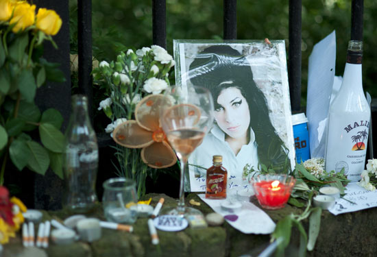 Bottles of alcohol, cigarettes and flowers line the wall in Camden Square