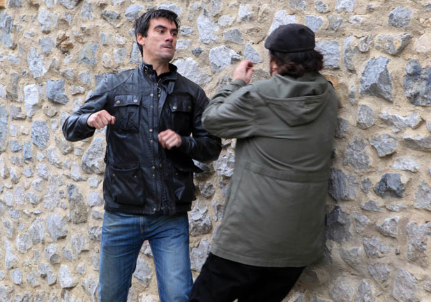 Cain Dingle (Jeff Hordley) punches Zak Dingle (Steve Halliwell) while Lisa Dingle (Jane Cox) watches on
