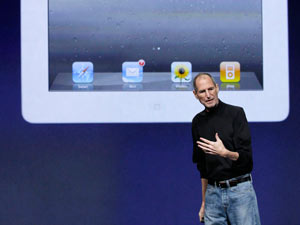 Steve Jobs stands under an image of the iPad 2 at an Apple event at the Yerba Buena Center for the Arts Theater in San Francisco, March 2011