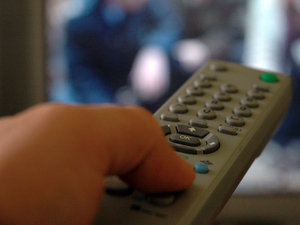 Image of a button being pressed on a TV remote control