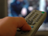 Image of a button being pressed on a TV remote control