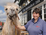 Kaza, a 10 month old camel outside the Horse Shoe Inn with owner Rebecca Fossett in Shipston-on-Stour
