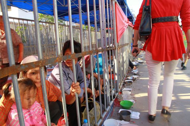 Beggars caged behind bars at temple fair to prevent harassment of tourists, Nanchang, Jiangxi Province, China -