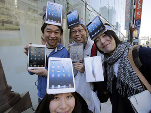 Customers Kazuki Miura, left, Mio Kawai, bottom, Hisanori Kogure, center, and Kota Suzuki show off Apple's iPad Mini after they bought at a store in Tokyo