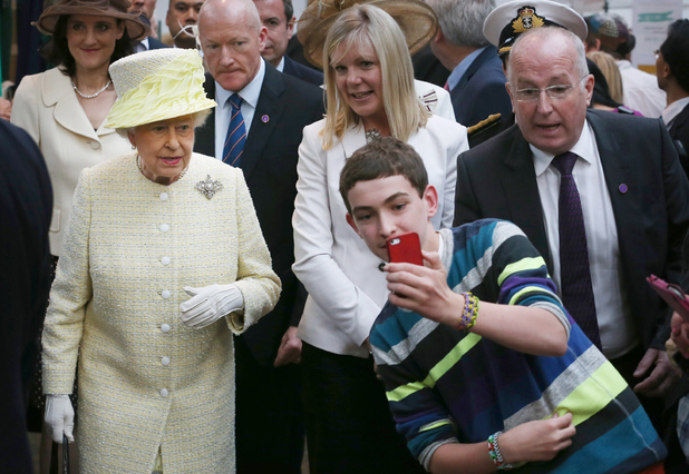 A teenager tries to take a selfie infront of Queen Elizabeth II during a walk around St. Georges Market in Belfast