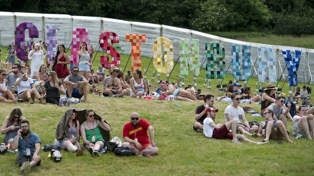 Revellers sit near a 'Glastonbury' sign after arriving to attend the Glastonbury Festival 2015