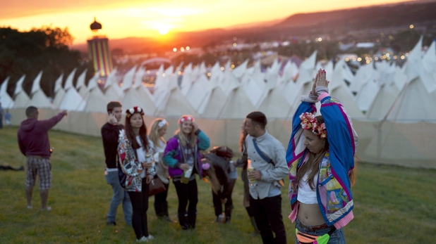 Revellers watch the sun set over the site at the Glastonbury Festival 2015